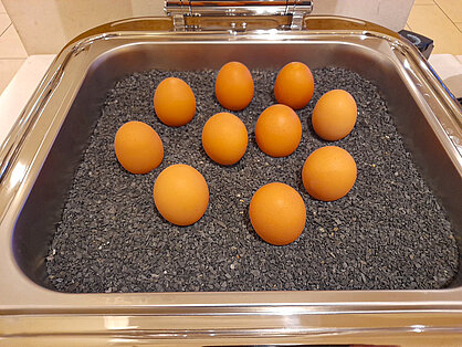 Gekochte Eier am Frühstücksbuffet Gekochte Frühstückseier auf schwarzem Granulat im Warmhaltebehälter