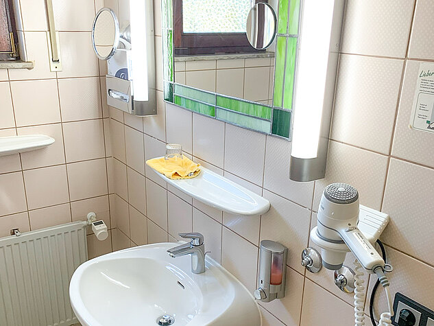 Hell beleuchtetes Bad mit Waschbecken und Föhn