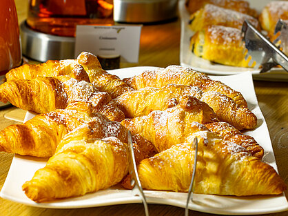 Frisch gebackene Croissants am Frühstücksbuffet Frisch gebackene Croissants mit Puderzucker am Frühstücksbuffet