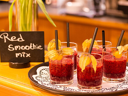 Roter Smoothie-Mix im Glas Roter Beeren-Smoothie mit Physalis und Strohhalm auf dem Frühstücksbuffet