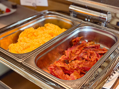 Frühstücksbuffet mit Rührei und knusprigem Bacon Rührei und knuspriger Bacon in Buffetbehältern beim Frühstück im Hotel Birkenhof