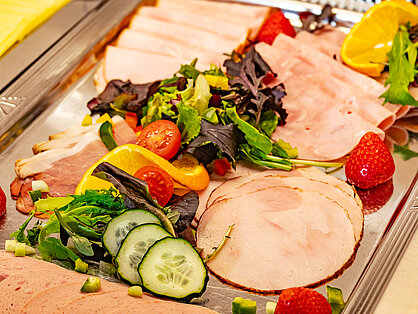 Wurst- und Schinkenplatte am Frühstücksbuffet Auswahl an Wurst und Schinken mit frischer Garnitur auf dem Frühstücksbuffet