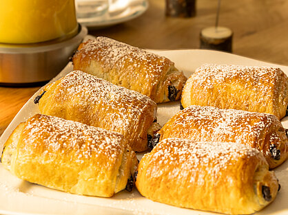 Schokoladengebäck auf dem Frühstücksbuffet Frisch gebackene Schokobrötchen mit Puderzucker auf dem Frühstücksbuffet
